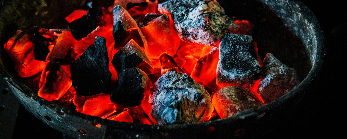 Tænd op i kamado: glødende stykker trækul i en rund kulkurv